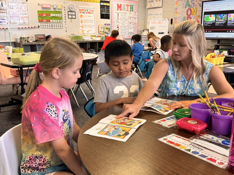 teacher working with two students at table 