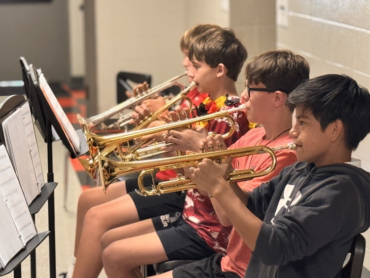 four male students playing trumpet 