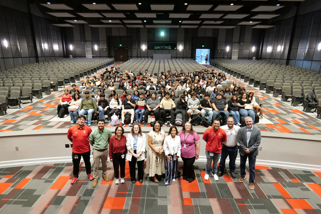 large group of students and adults (in foreground) in high school auditorium