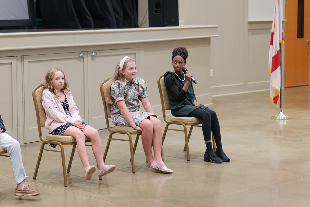 Young students on education panel; one on right holding a microphone.