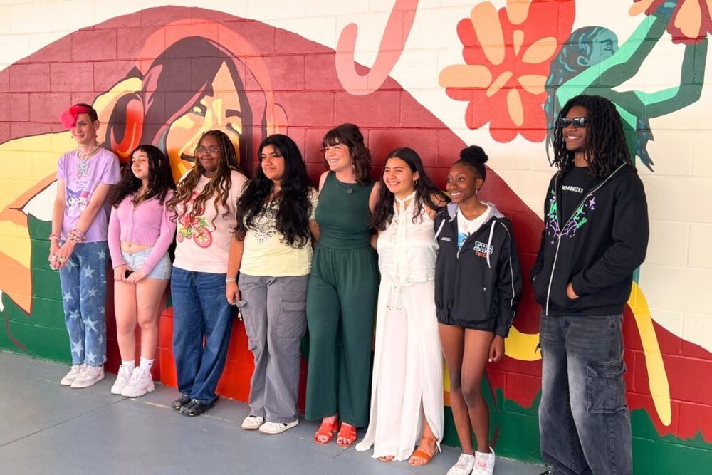 Jenna Horner (in green) poses for a photo with some of the students who helped contribute to the mural. Photo by Nick Anschultz