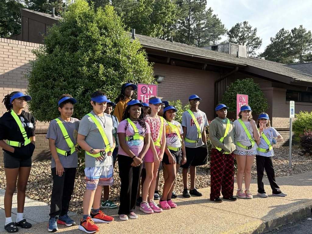 a group of students in safety gear standing on a sidewalk