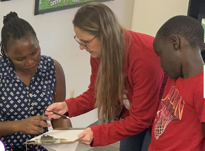 Teacher assisting parent with registration paperwork while student watches nearby