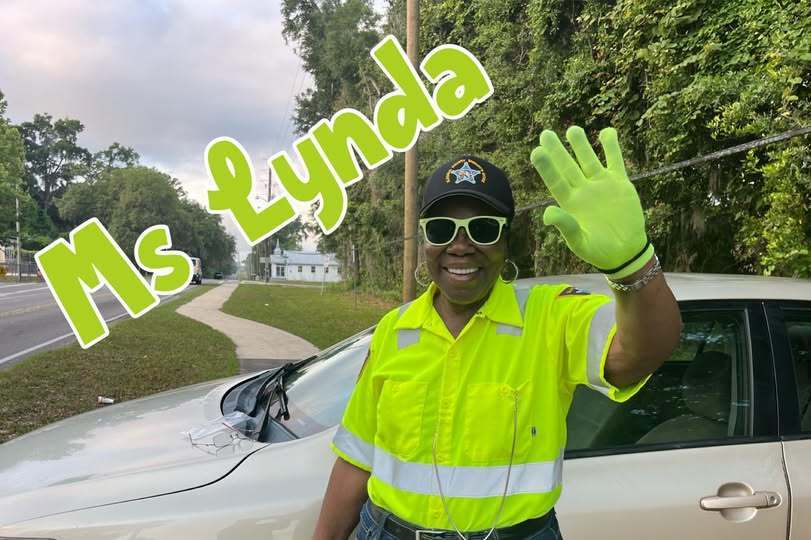crossing guard waves at camera