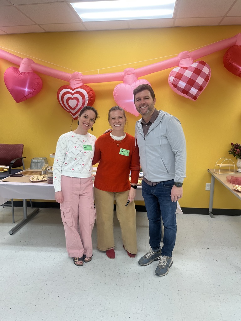 two women and 1 male in front of heart balloons
