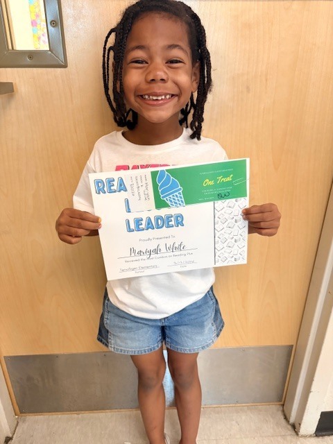 student in front of a door with a certificate