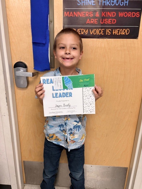 student in front of a door with a certificate