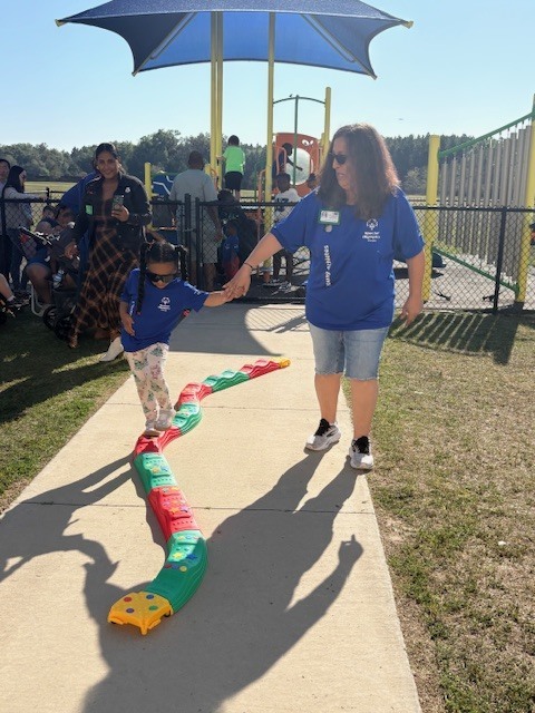 student walking on balance beam with teacher