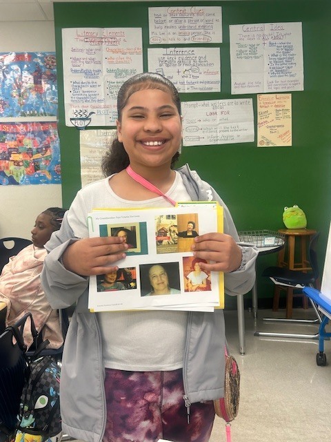 student holding photos of part of her project