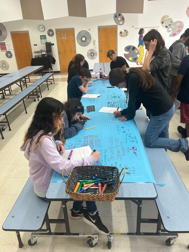 Students use coloring utensils to write on bulletin board paper