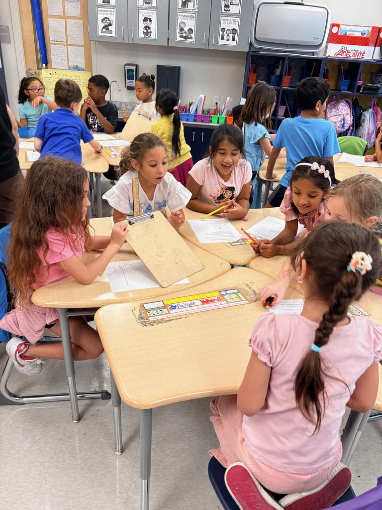 students working at tables with clipboards, toy cars, and rulers