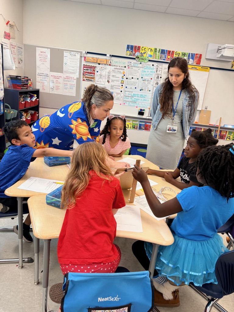 students working at tables with clipboards, toy cars, and rulers