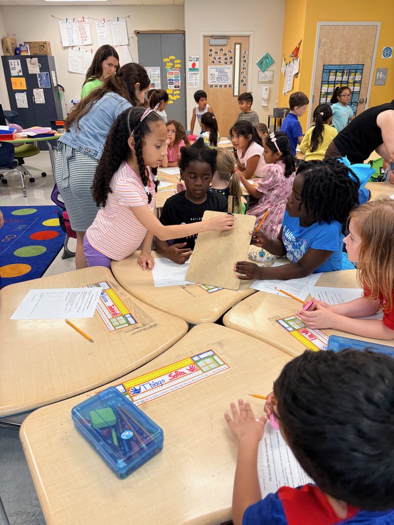 students working at tables with clipboards, toy cars, and rulers
