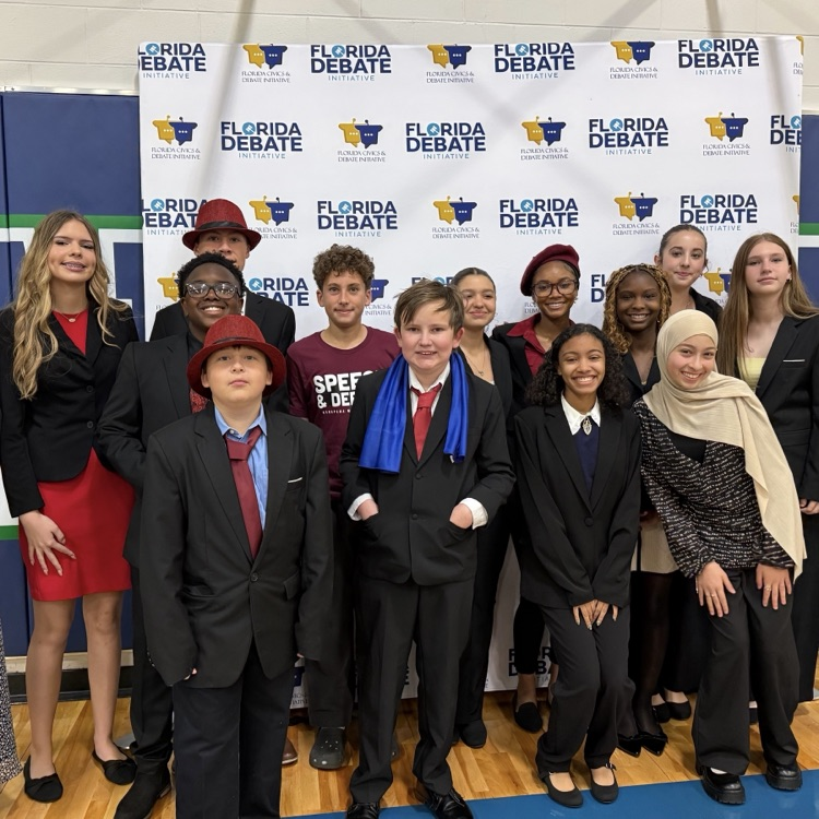 students in a gymnasium in front of a speech and debate background 
