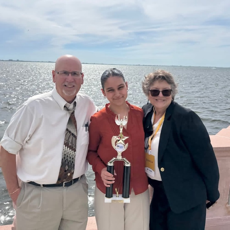 Mr and Mrs Barron with a former student holding a trophy  