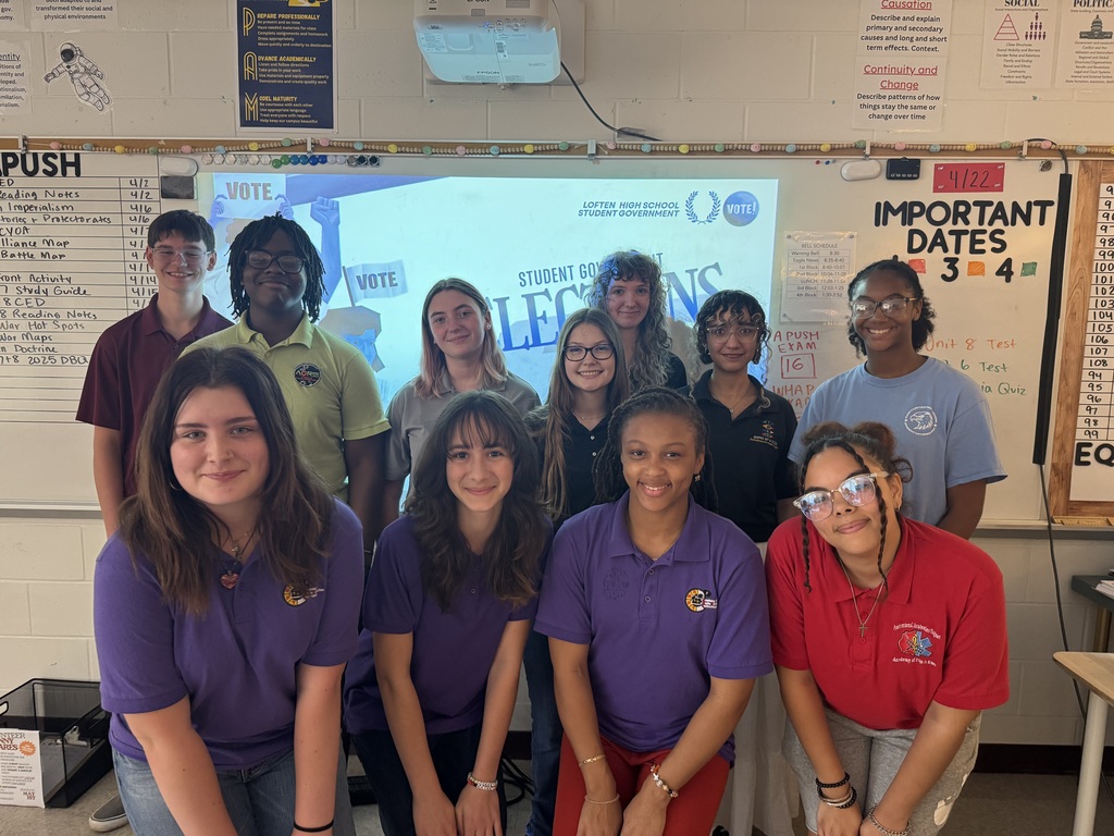 11 students stand in front of a white board