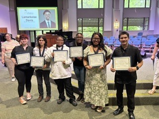 students hold certificates and stand together
