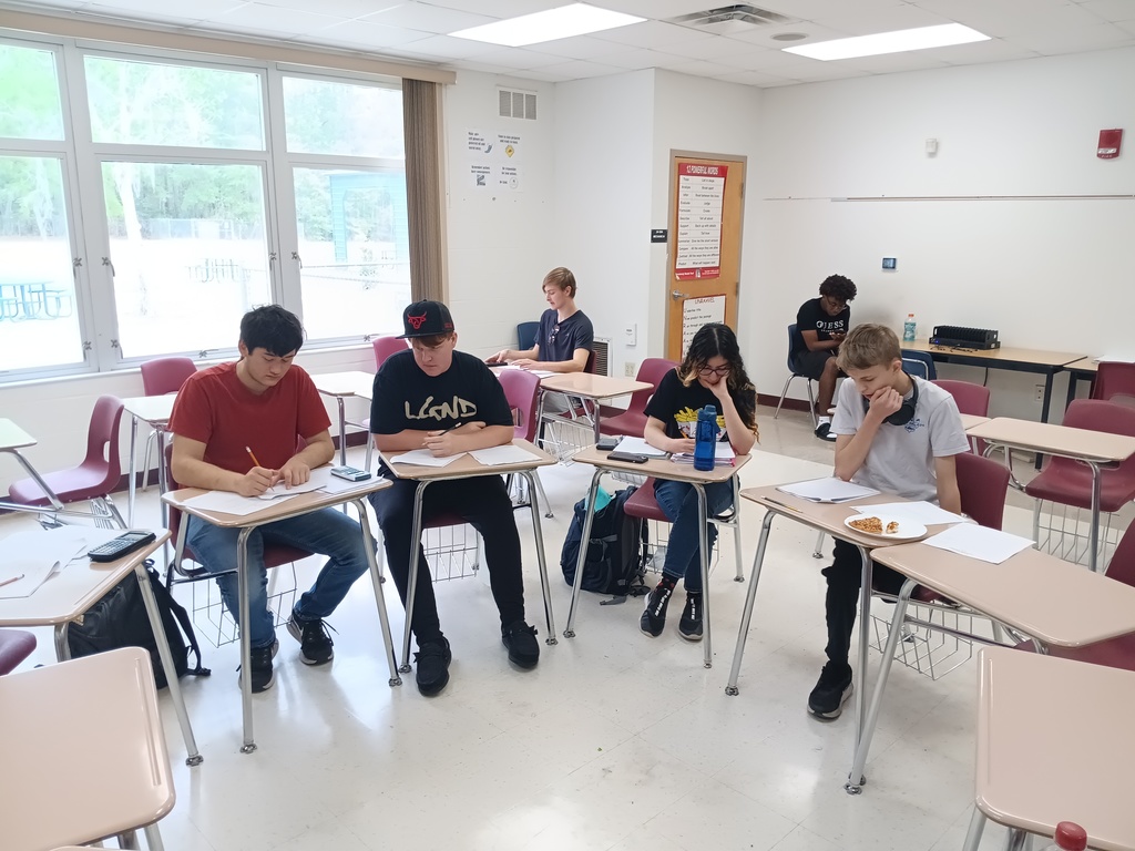 5 students sit at desks studying