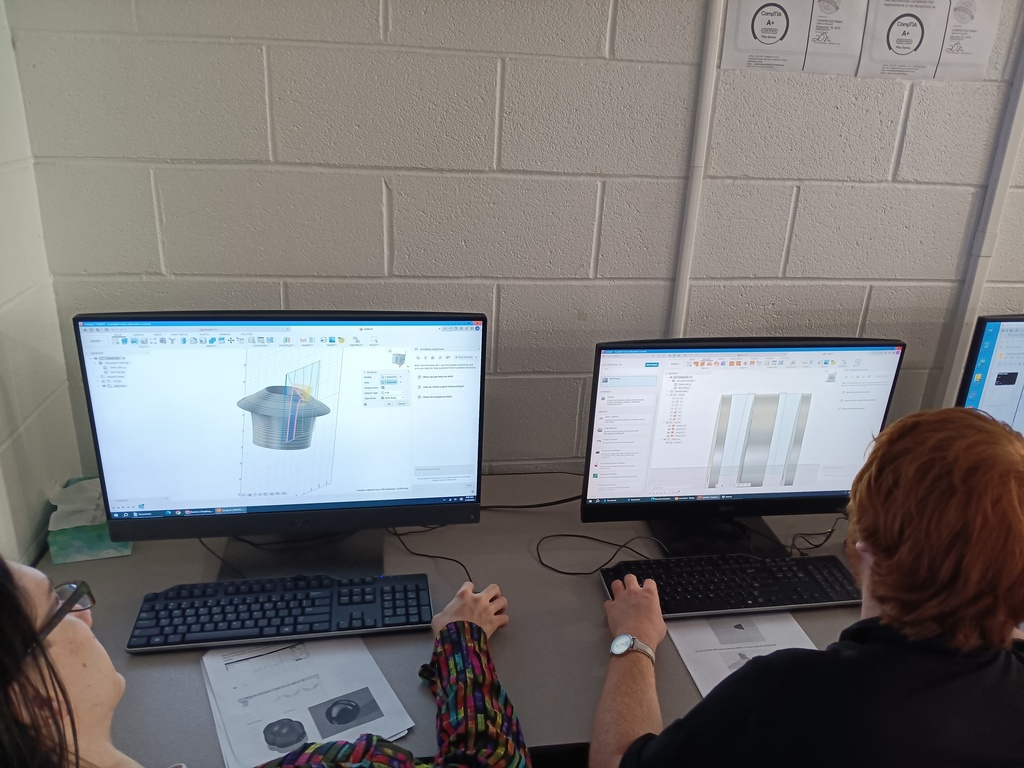 two computers are shown, and the backs of 2 students' heads