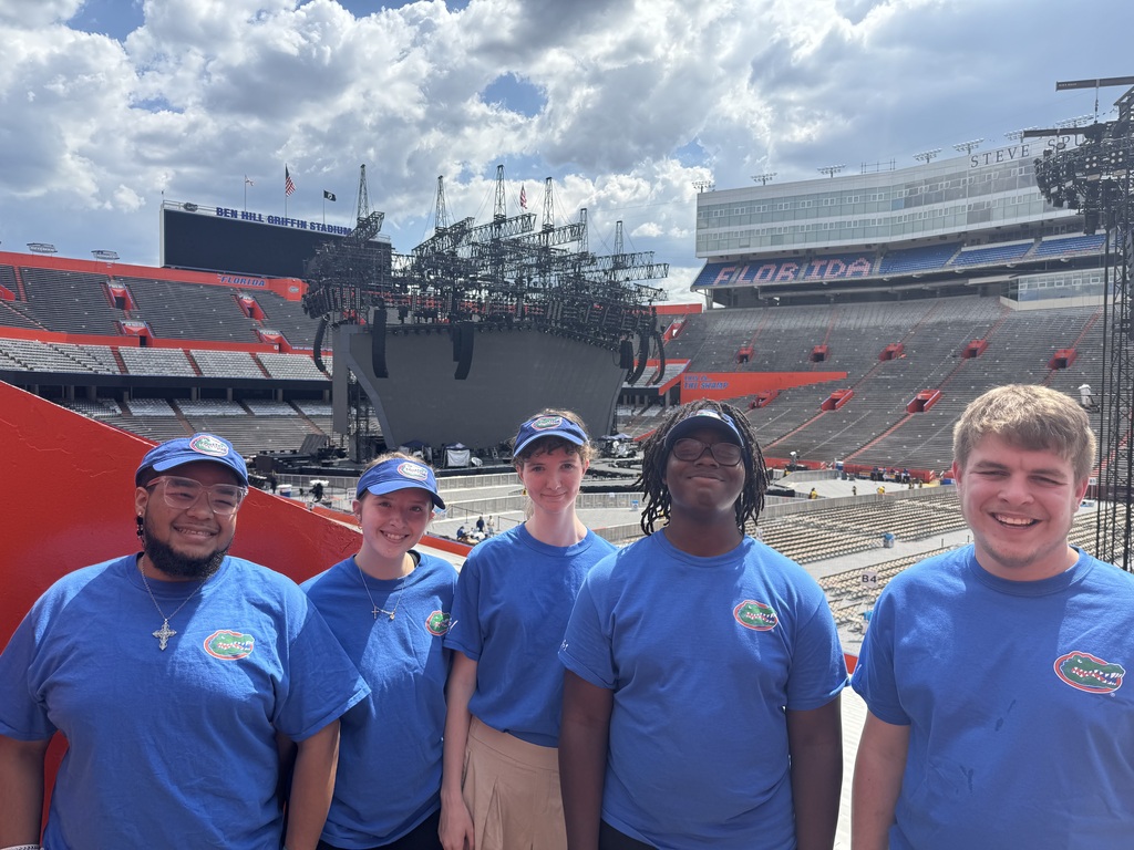 5 students in blue shirts at Ben Hill Griffin stadium