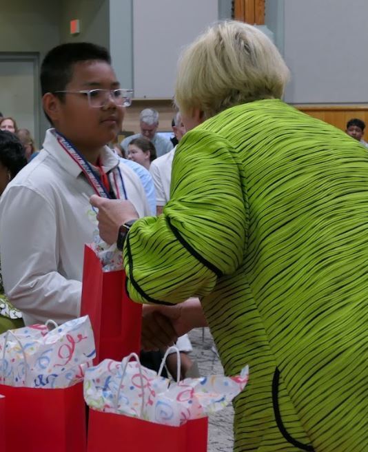 student getting a medal from a woman in green