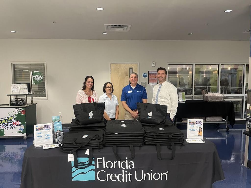 picture of four people behind a table with Florida Credit Union written on the tablecloth