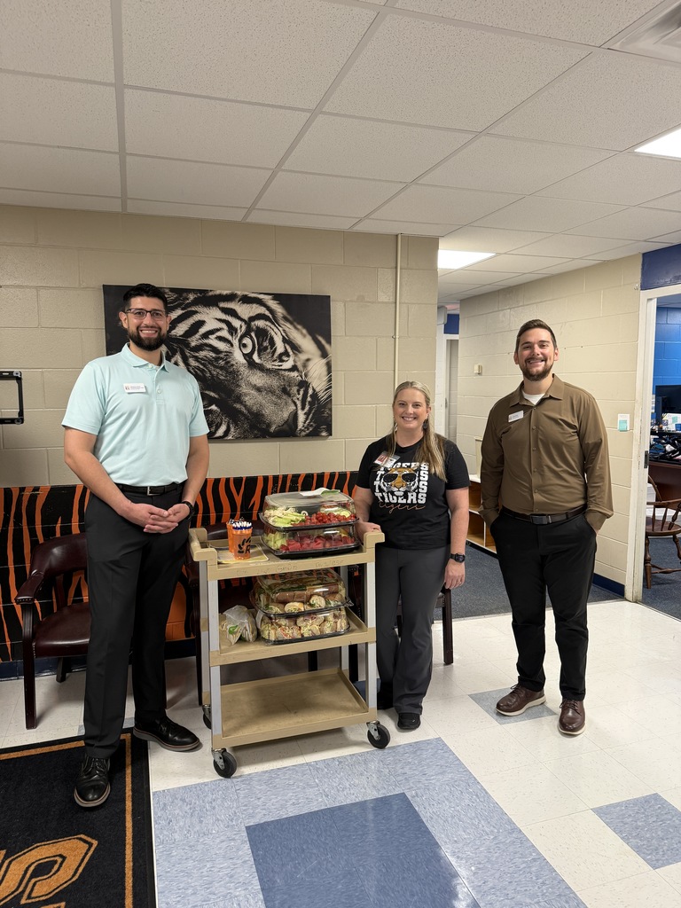 Photo shows two employees delivering Publix lunch trays to the principal of Glen Springs Elementary..