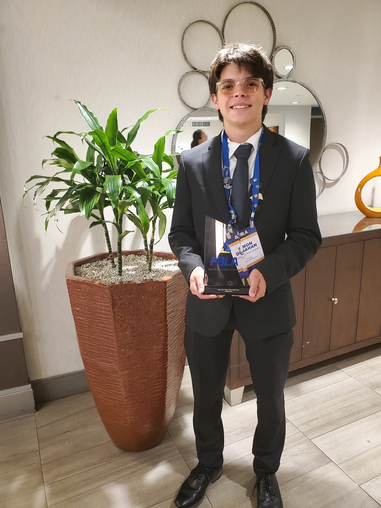 A person in a suit holding a tropy.