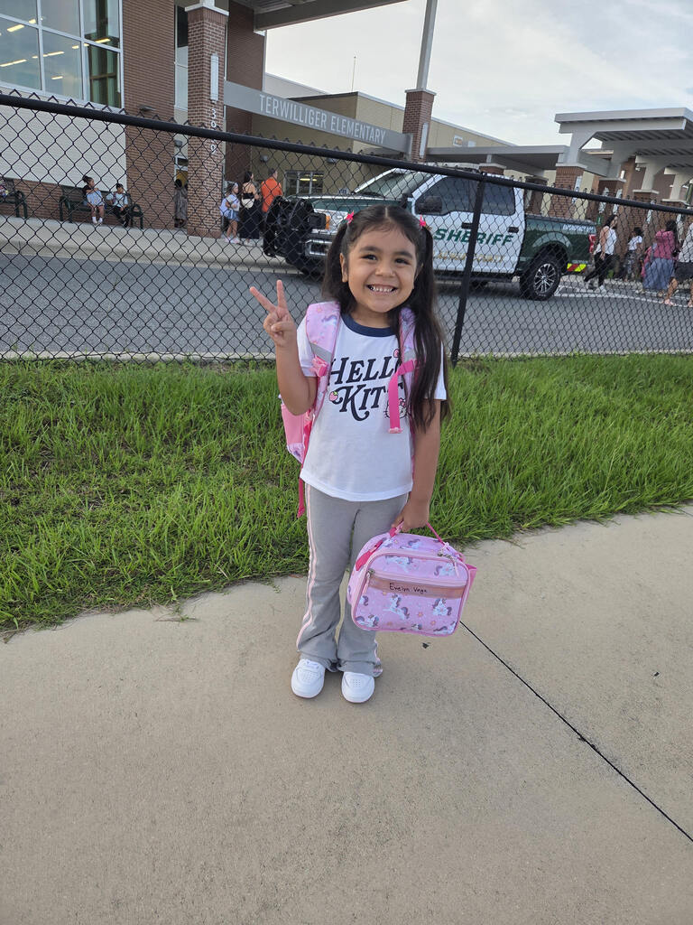 student smiling in front of school
