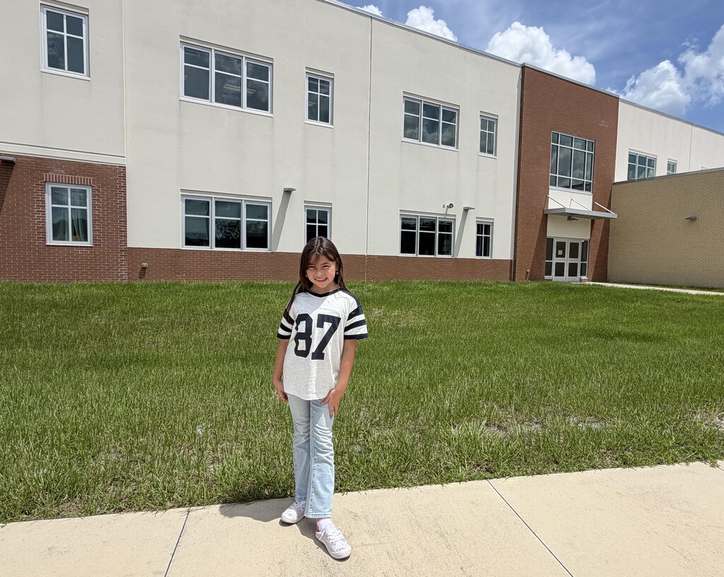 girl smiling in front of school