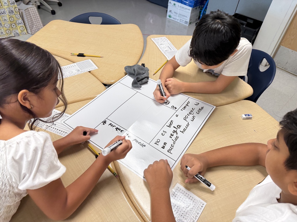 three students working at a desk