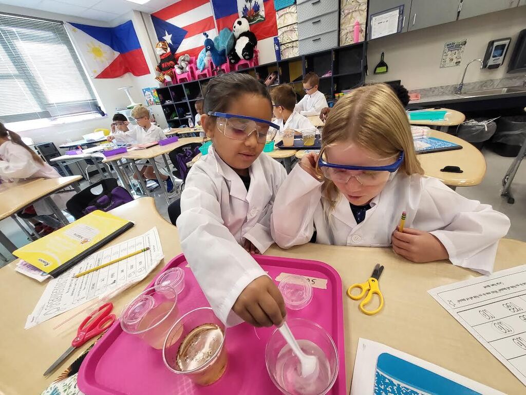two girls in lab coats working at desks