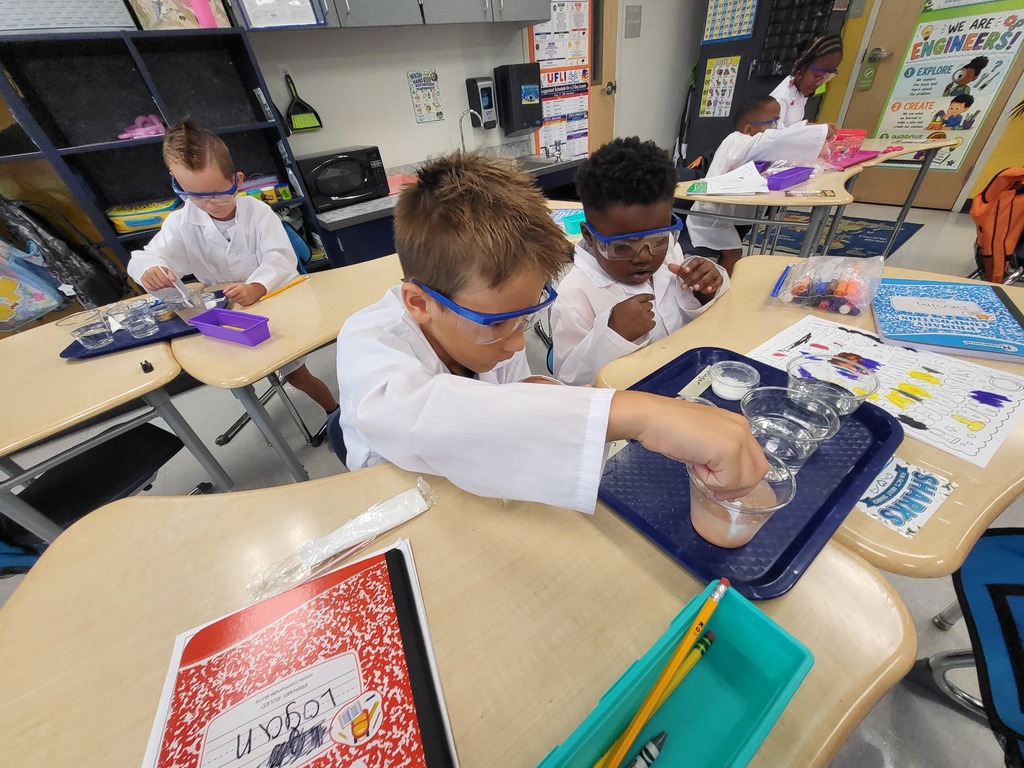 students in lab coats at a desk