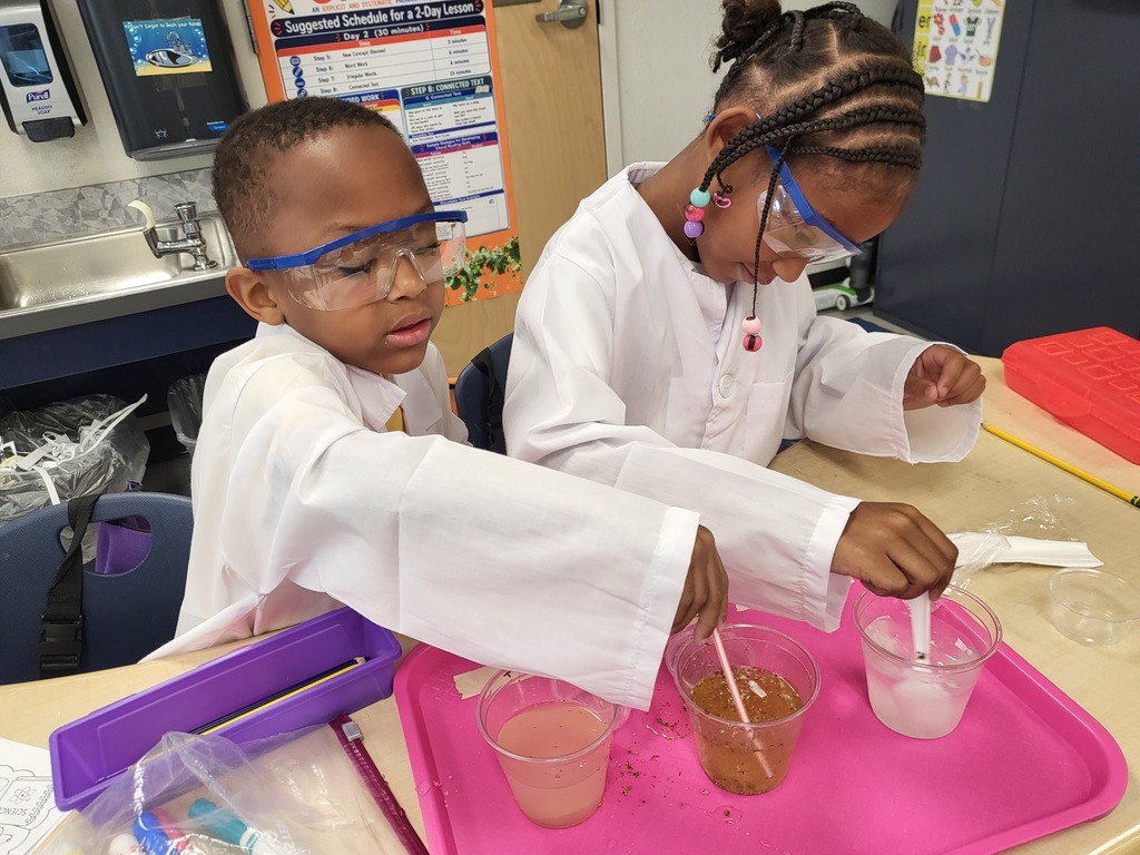 two students in lab coats at a desk