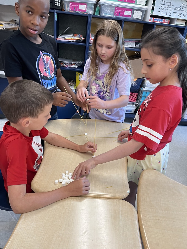 four students building with spaghetti and marshmallows