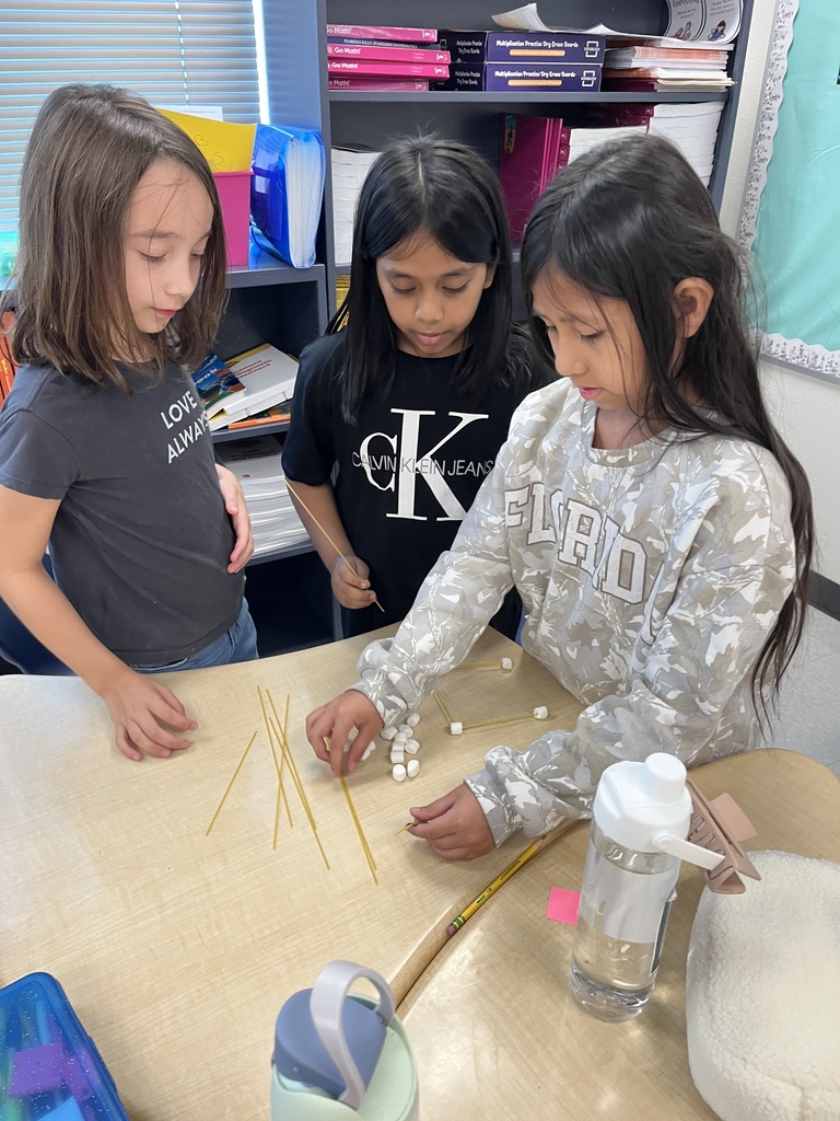 three students building with spaghetti and marshmallows