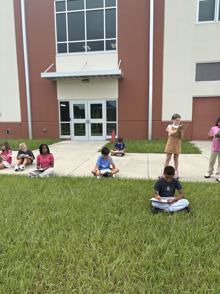 student sitting in the grass taking notes