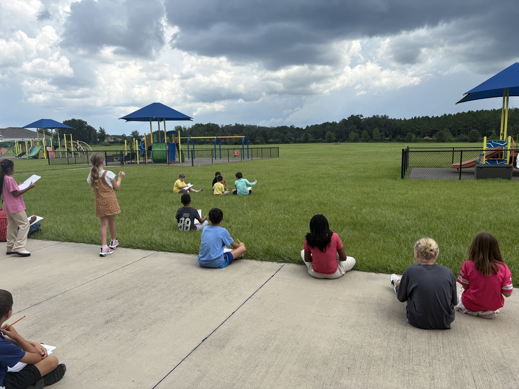 students sitting outside taking notes