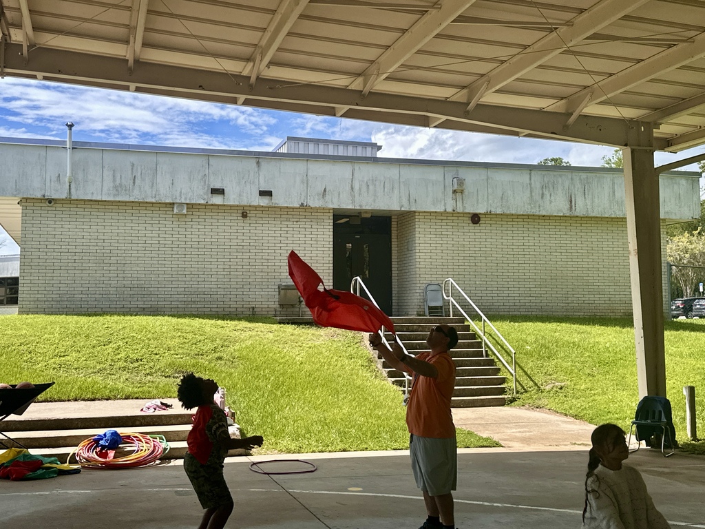Students working together to catch ball in parachute.
