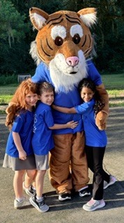 Roary the Wiles Wildcat mascot celebrating with students at the Wiles 2026 Fun Run.