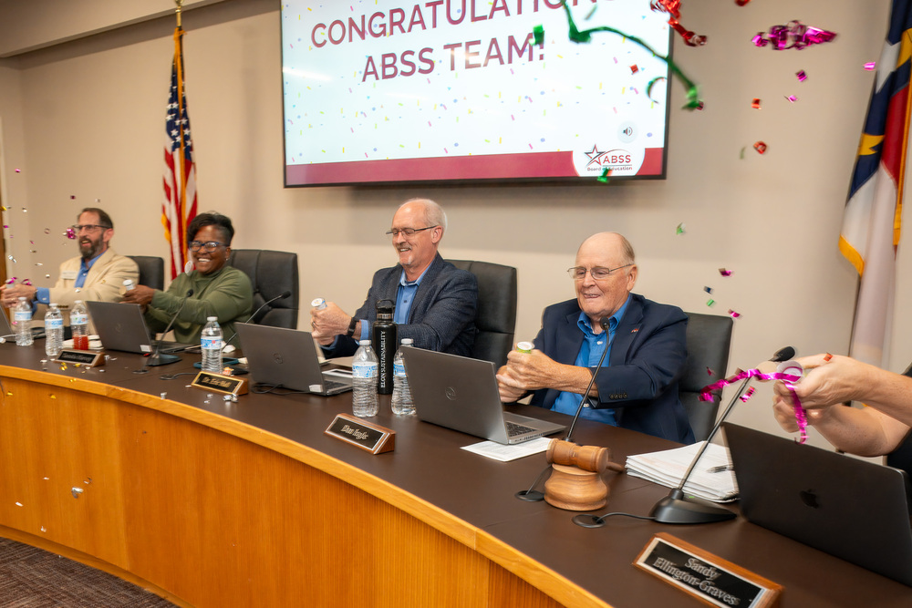 Four Board of Education members celebrating positive academic results with party poppers.