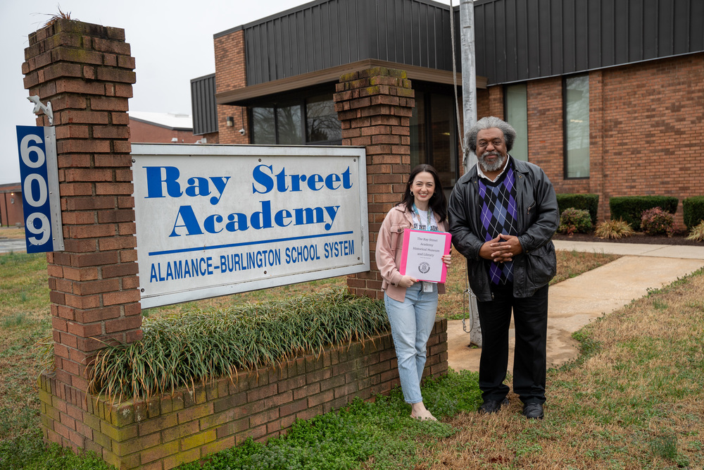 Mary Moorhouse and James Shields standing beside Ray Street Academy sign
