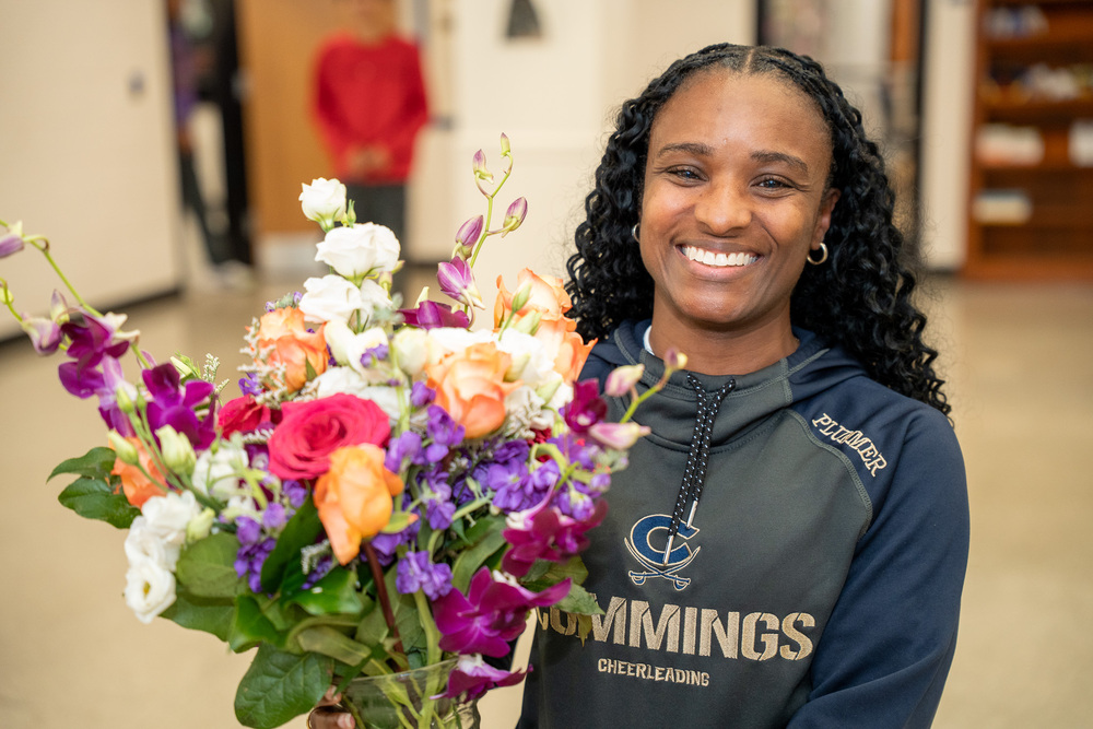 Jasmine Plummer wearing a blue and gray Cummings hoodie holding a vibrant bouquet of flowers