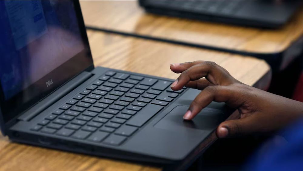 A child's hand is using the touchpad on a chromebook
