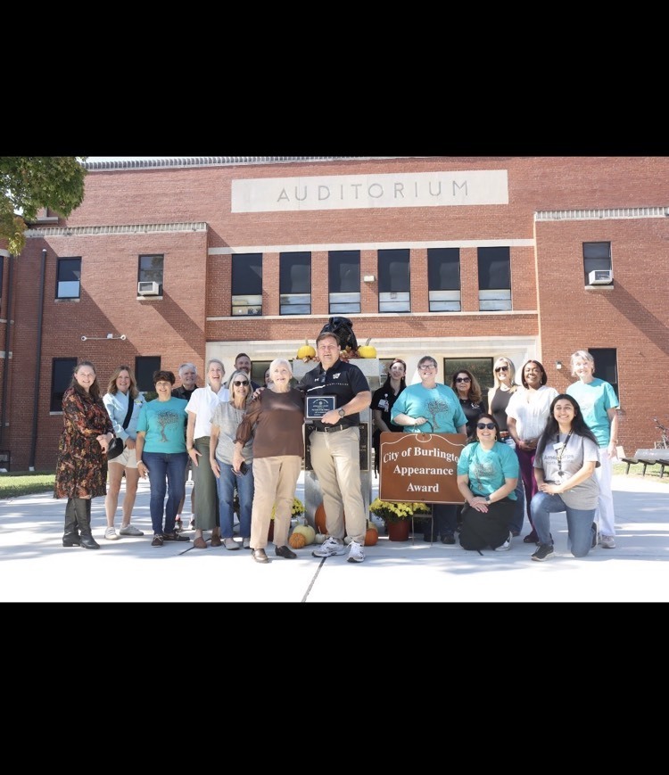 Community members, PTSO members, and Principal Bryan stand around the bulldog statue with an award plaque.