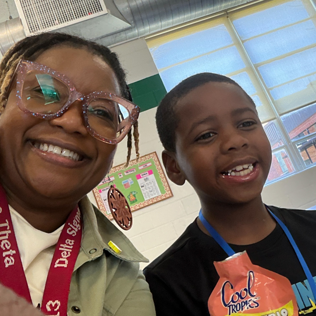 Principal Goldsby takes a smiling selfie with an elementary student in the school cafeteria