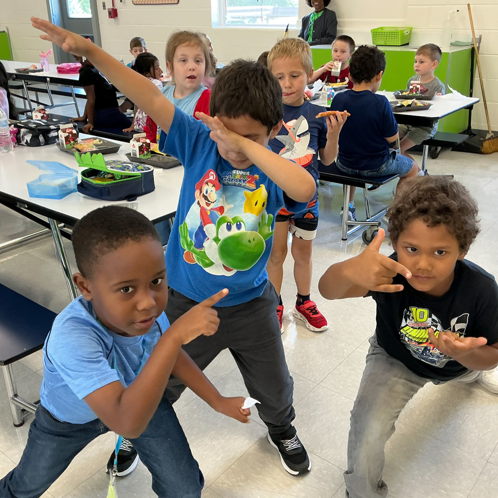 Elementary students strike a variety of poses at lunch in a school cafeteria