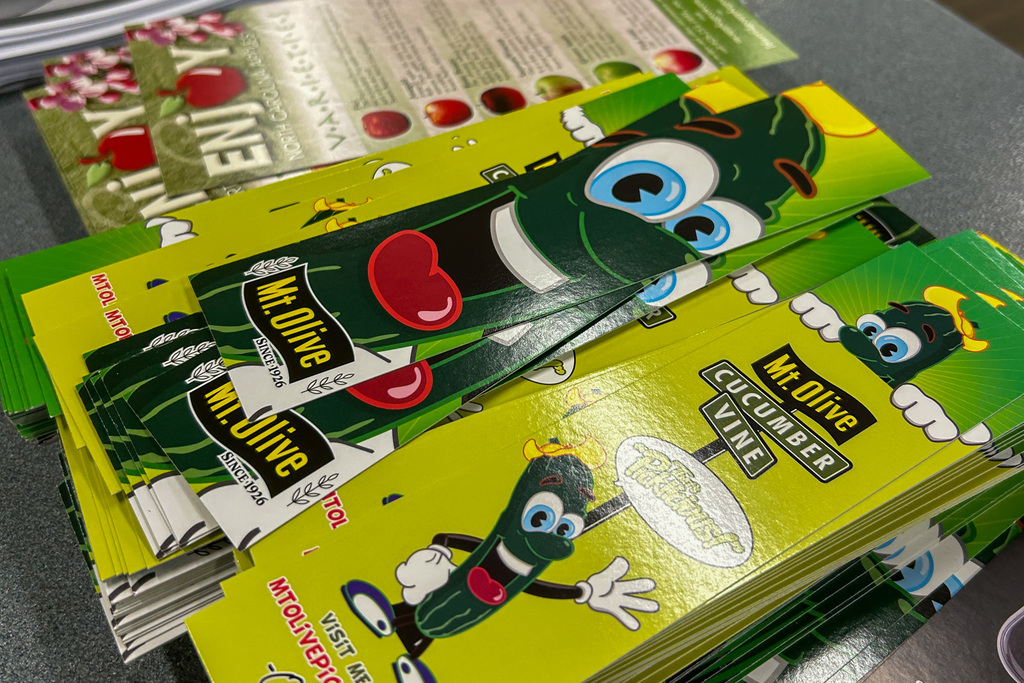 A stack of children's agricultural education materials featuring a cartoon green tractor character with large googly eyes and a red tongue. The materials appear to be branded with "Hi-Olive" and "Cucumber Steve" characters designed to teach kids about farming.