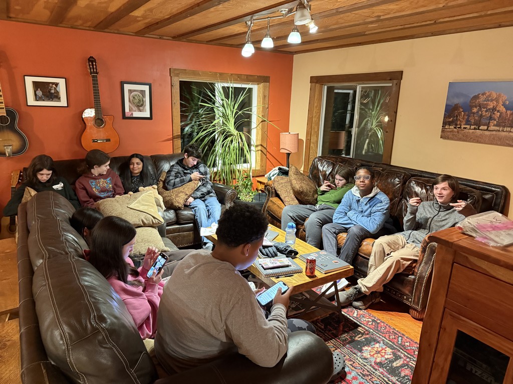Students relaxing and gathered in a cozy living room during their Yellowstone trip with leather couches and warm lighting
