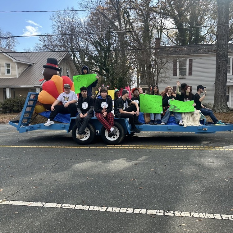 students riding on a blue trailer with an inflatable turkey 